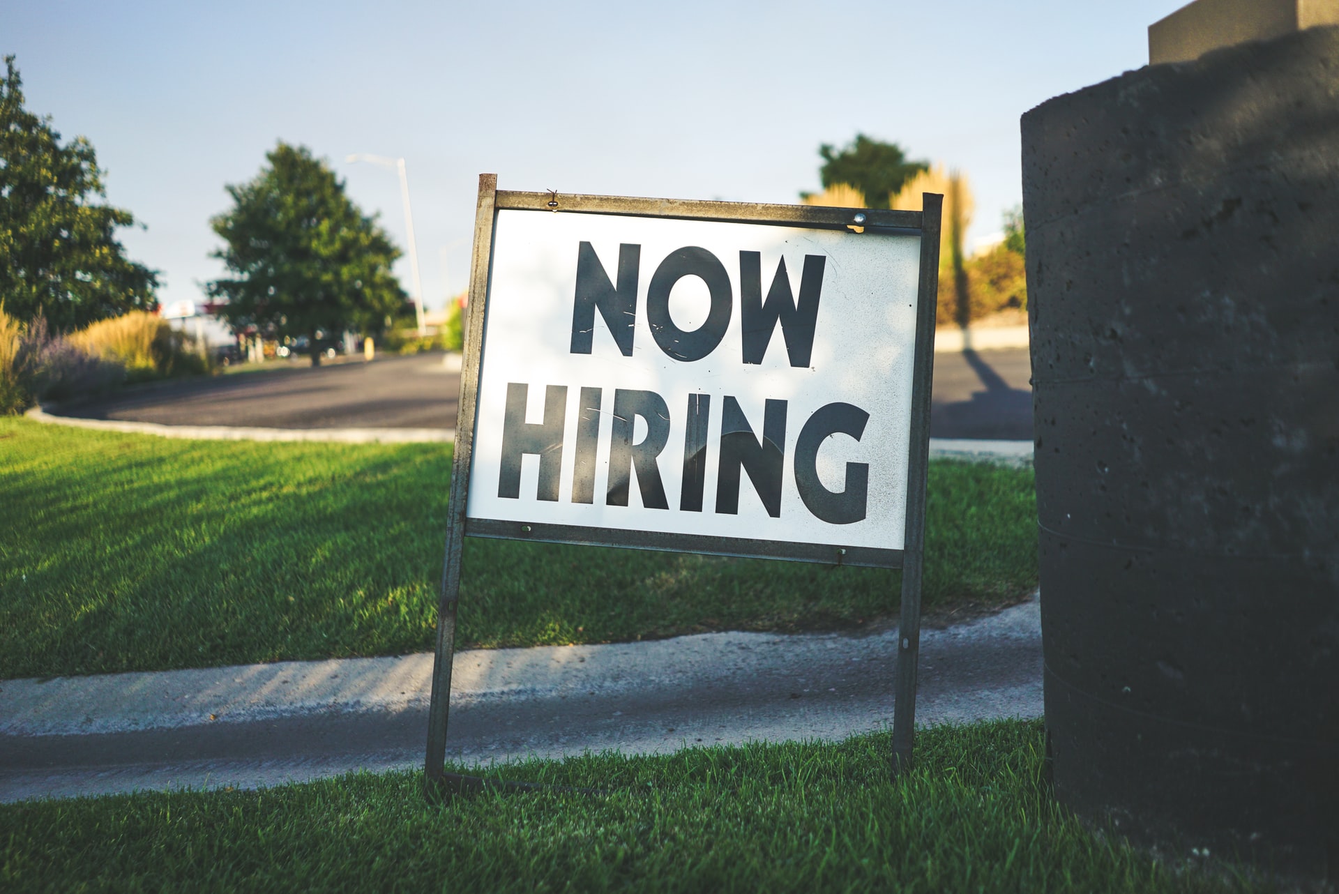 Now hiring sign on a patch of grass