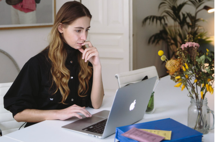 VA working at a desk with a notepad and laptop in a modern office