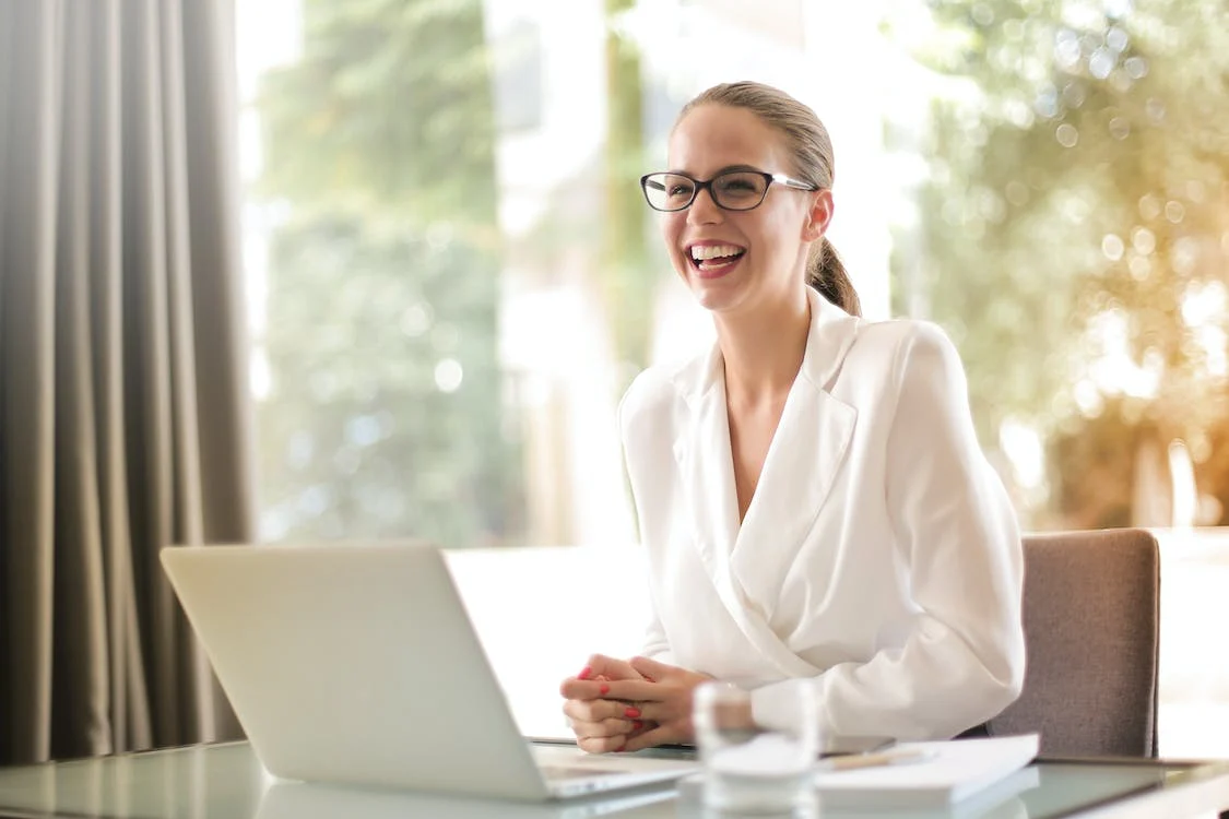 Smartly dressed woman laughing at her desk