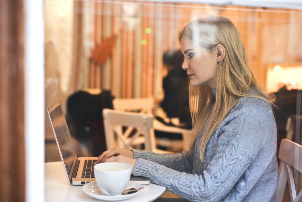 A PA for a celebrity sits in a cafe working on her laptop.