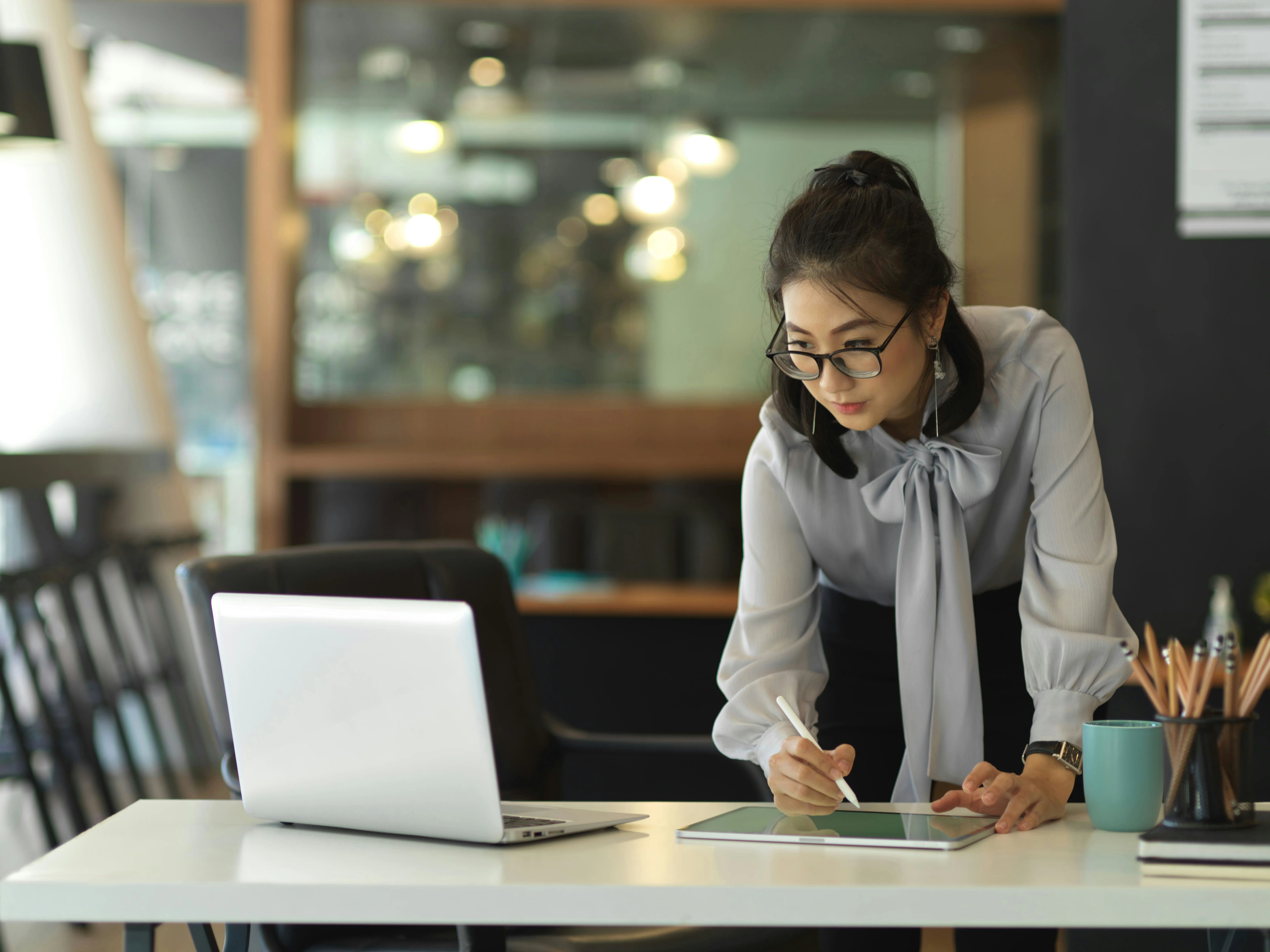 A personal assistant takes notes from her computer to a notepad about an important meeting.
