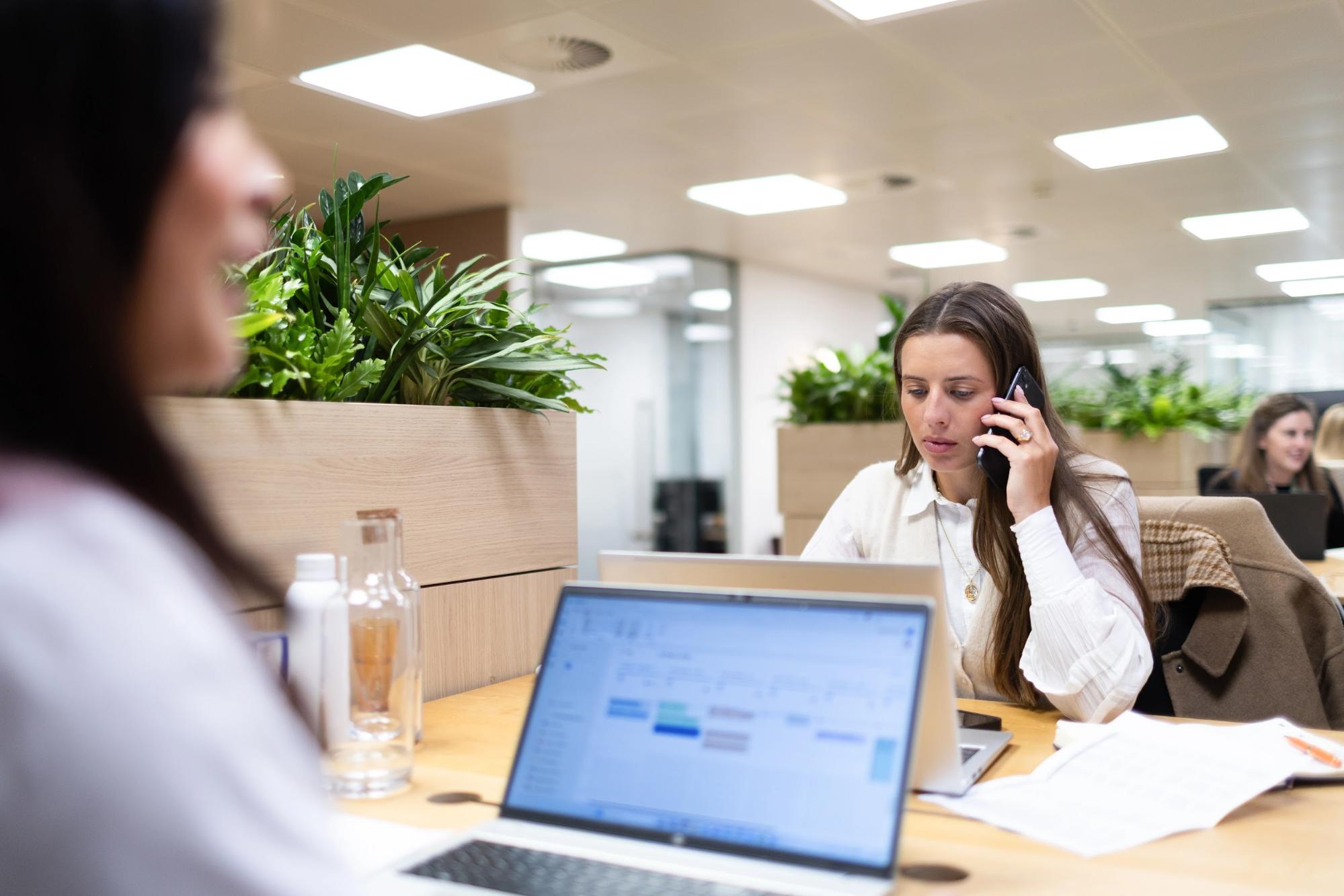 Business support recruitment professional on the phone at a laptop in a corporate finance office