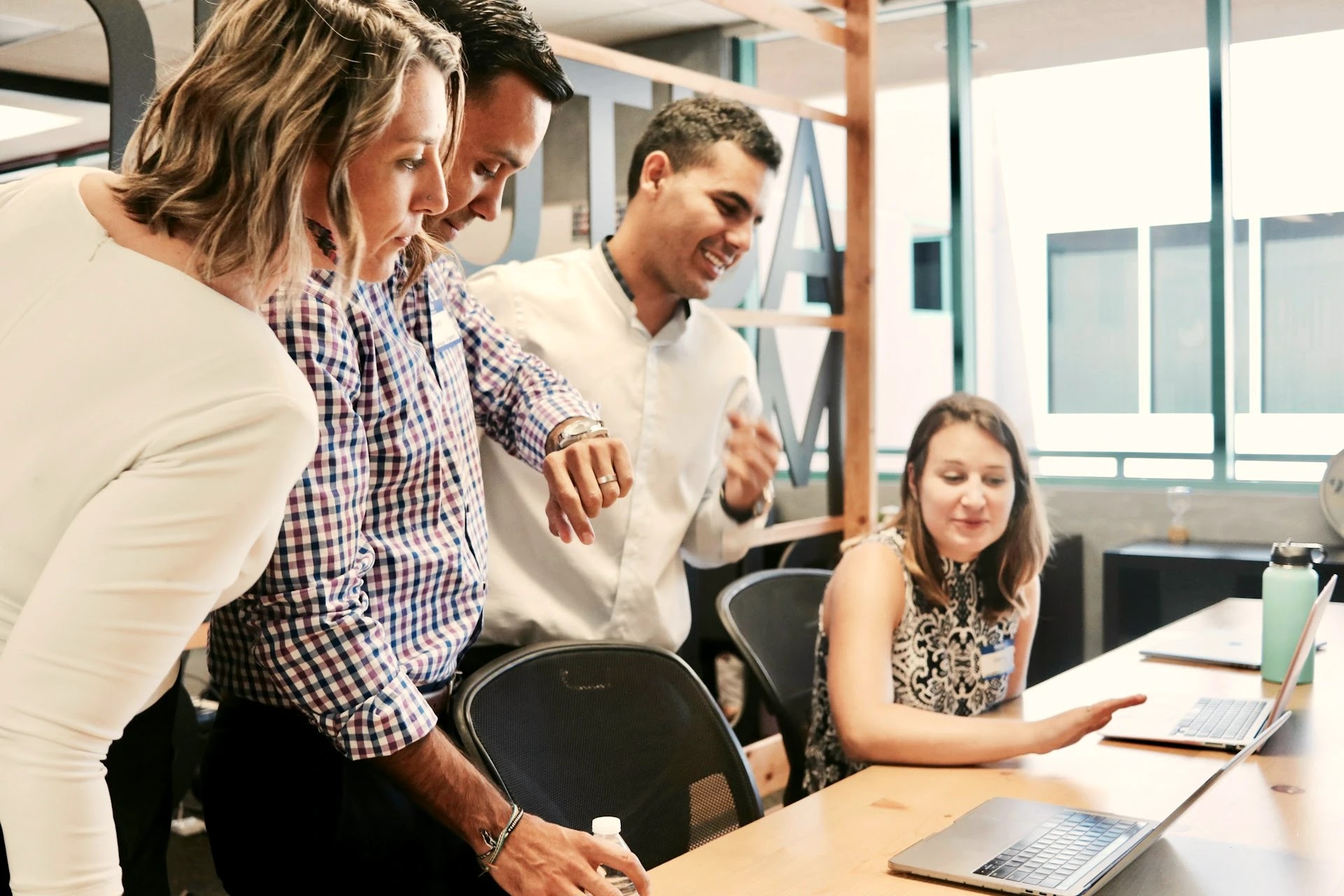 Consulting team gathered around a colleague's laptop collaborating in a meeting room 