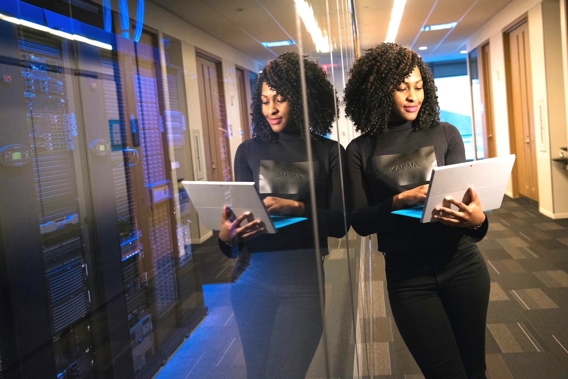 IT professional holding a laptop beside server racks in a data centre corridor
