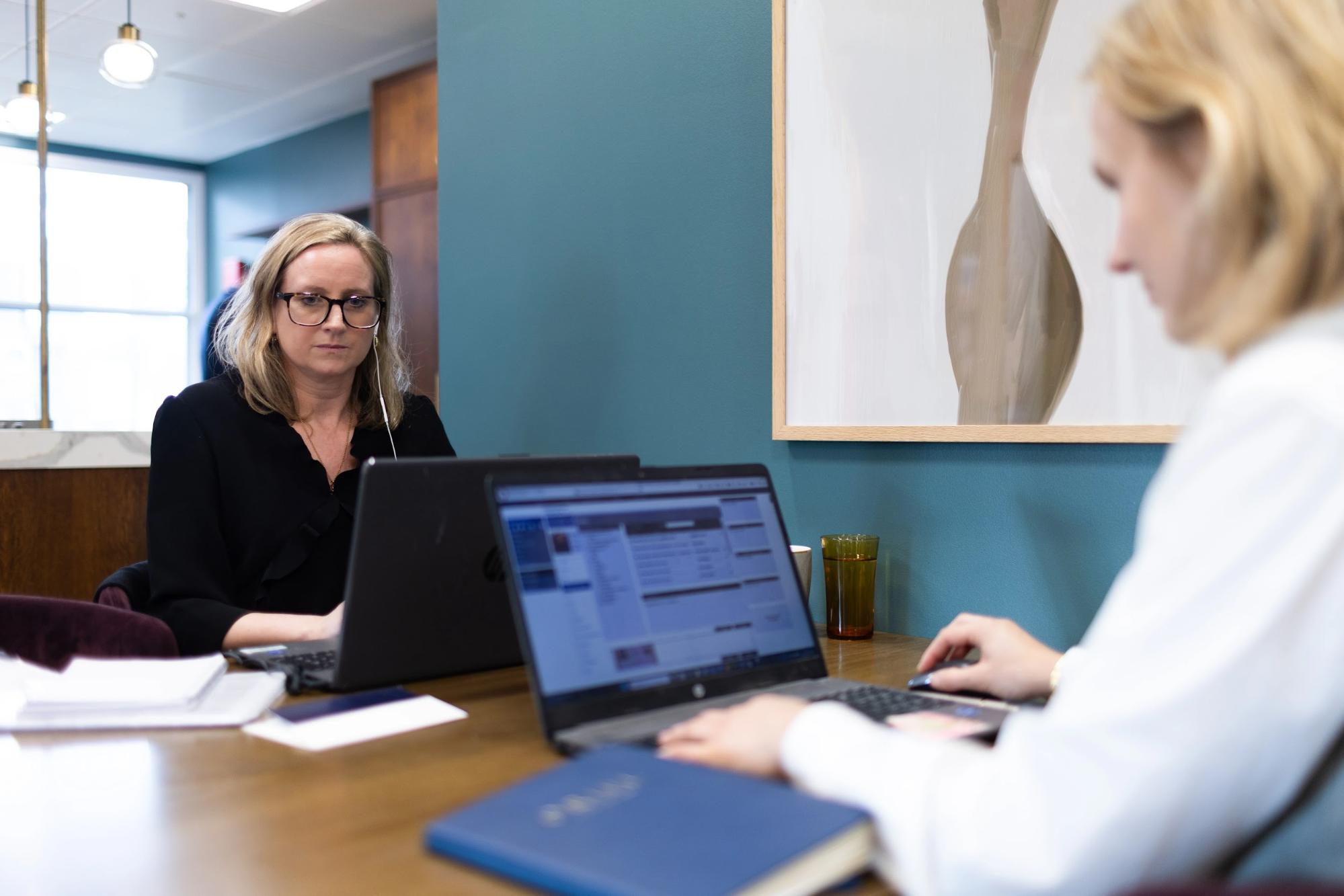 Two luxury recruitment consultants working at laptops in an Oriel Partners office meeting room