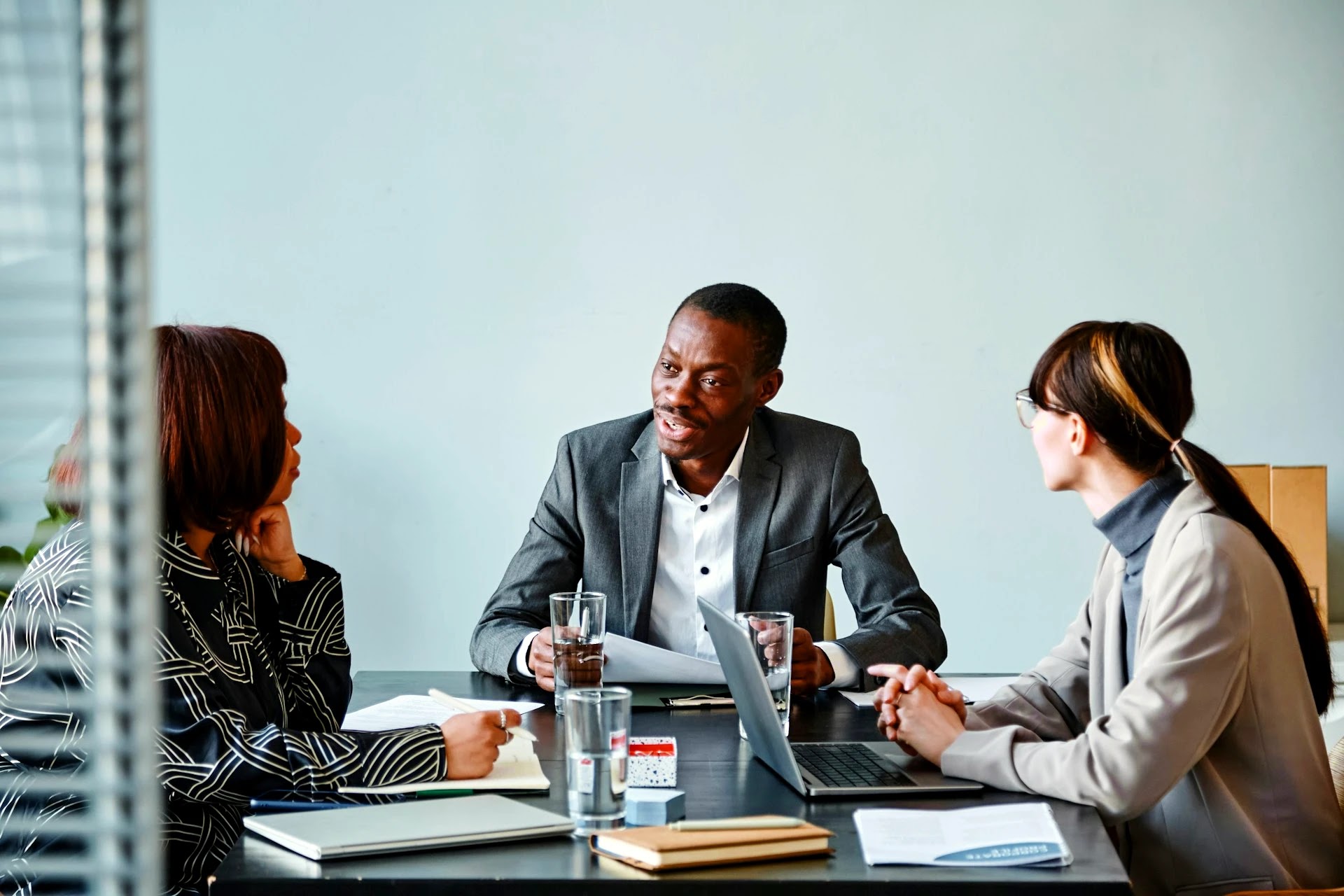 Three professionals in a focused business meeting around a conference table