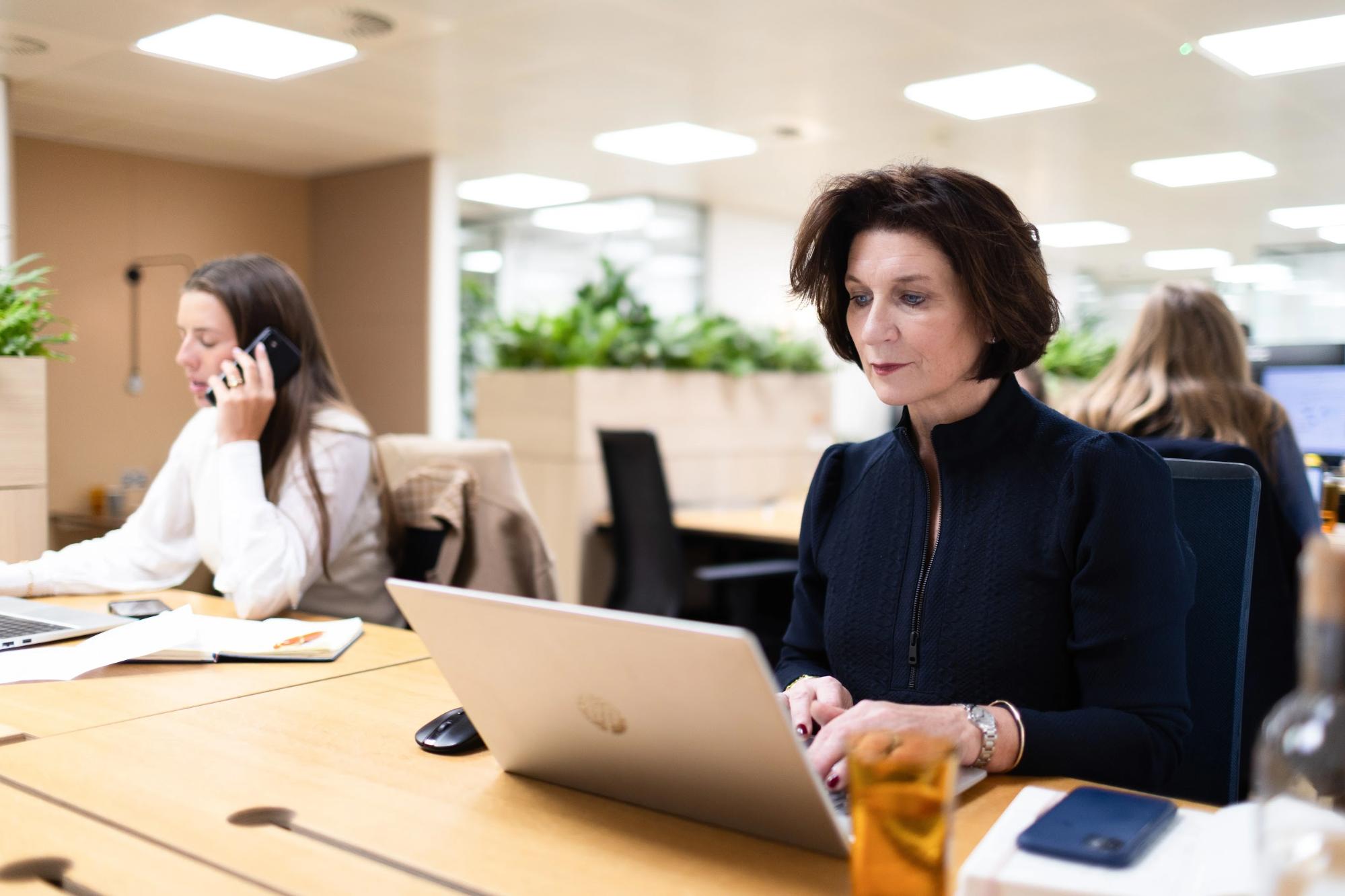 Senior recruitment consultant working at a laptop in a busy open-plan consultancy office