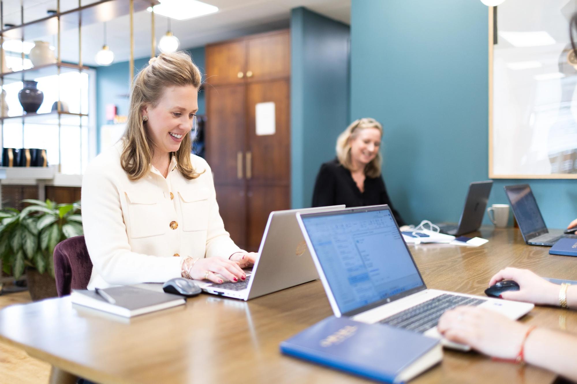 Business support professionals working on laptops in a bright plant-filled creative office