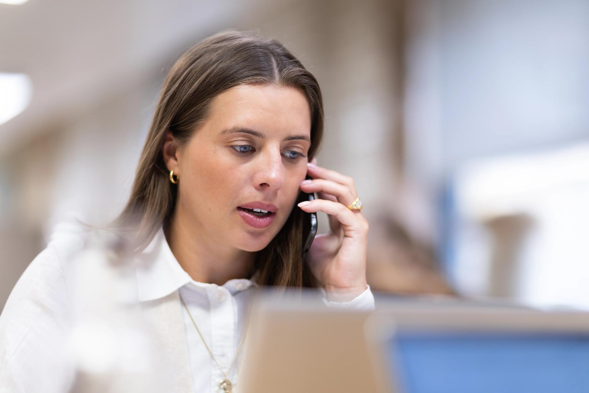 Fintech recruitment professional concentrating on a phone call at her desk