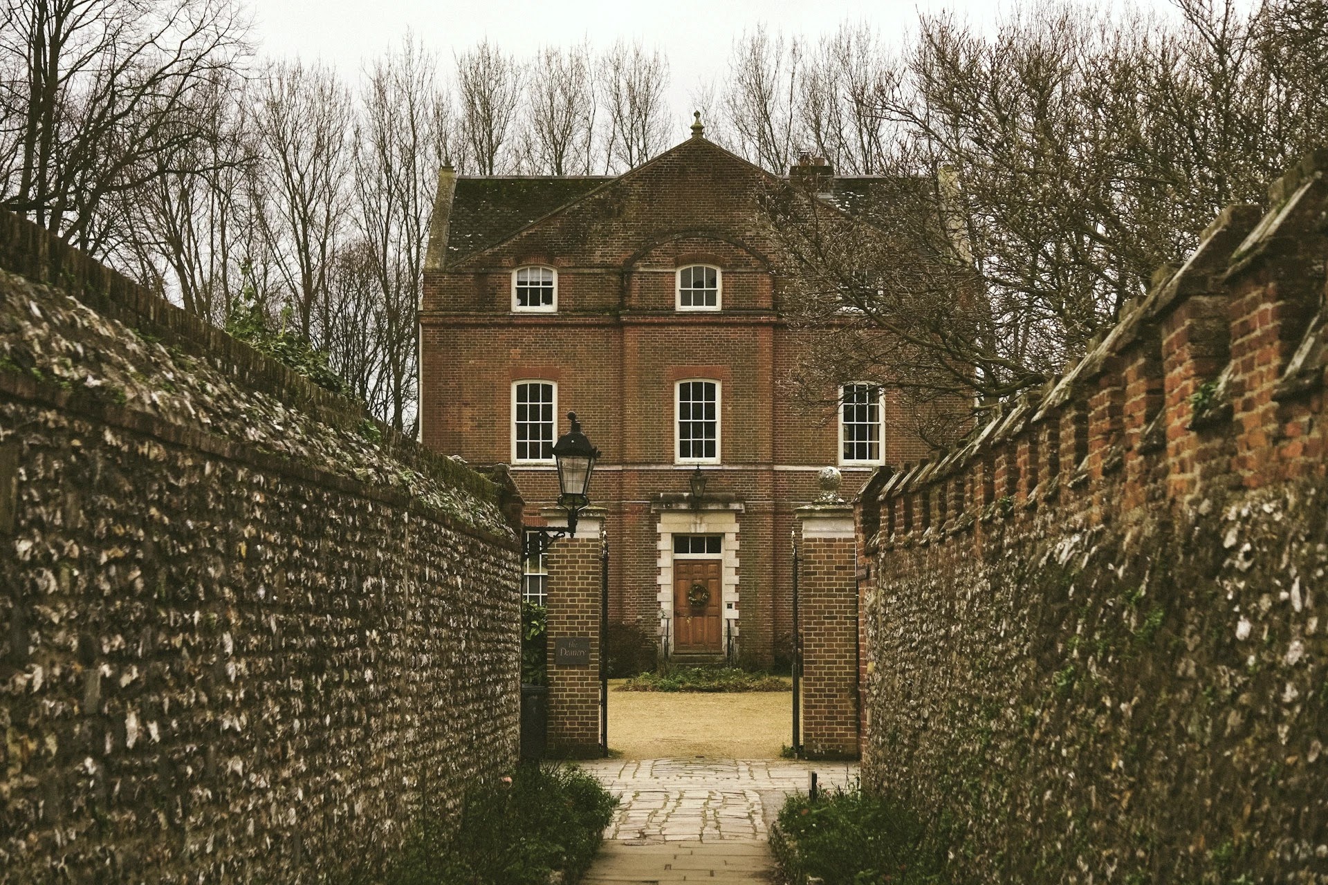 Georgian red-brick country house set behind a walled flint-lined entrance path