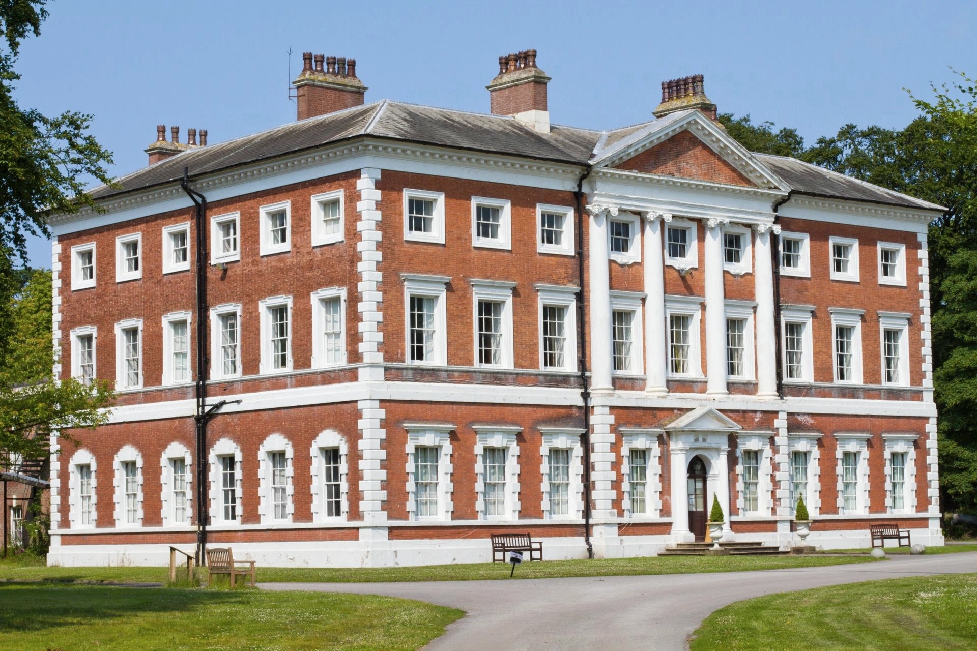 Grand red-brick Georgian country mansion with white stone detailing and front lawn