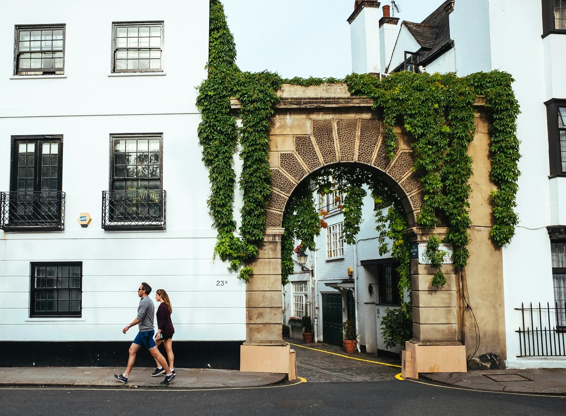 Ivy-clad archway leading to a private mews in an affluent UK neighbourhood