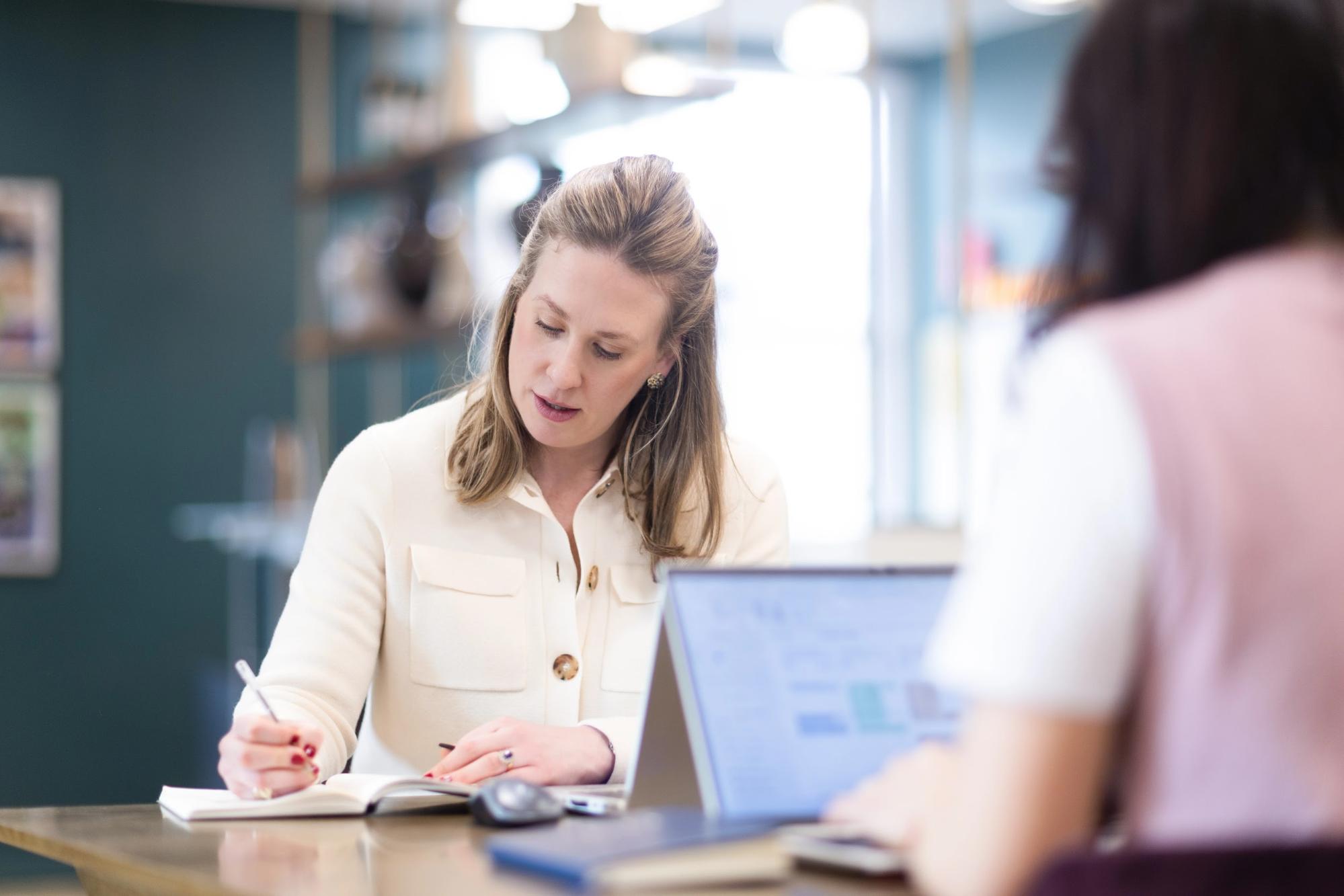 Property recruitment consultant taking notes during a client meeting in a relaxed office setting