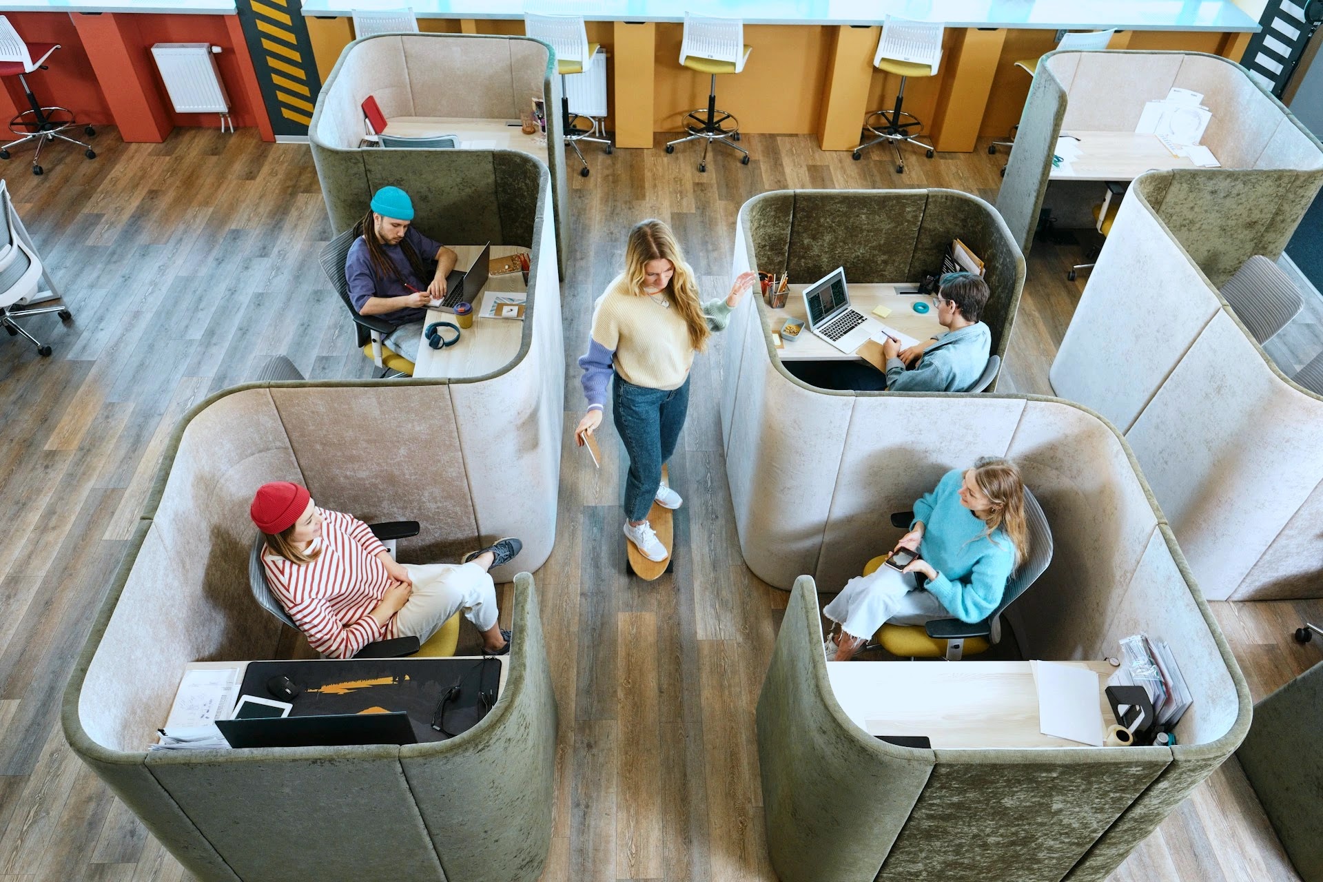 Overhead view of a scale-up team working in padded booths across an open-plan co-working office