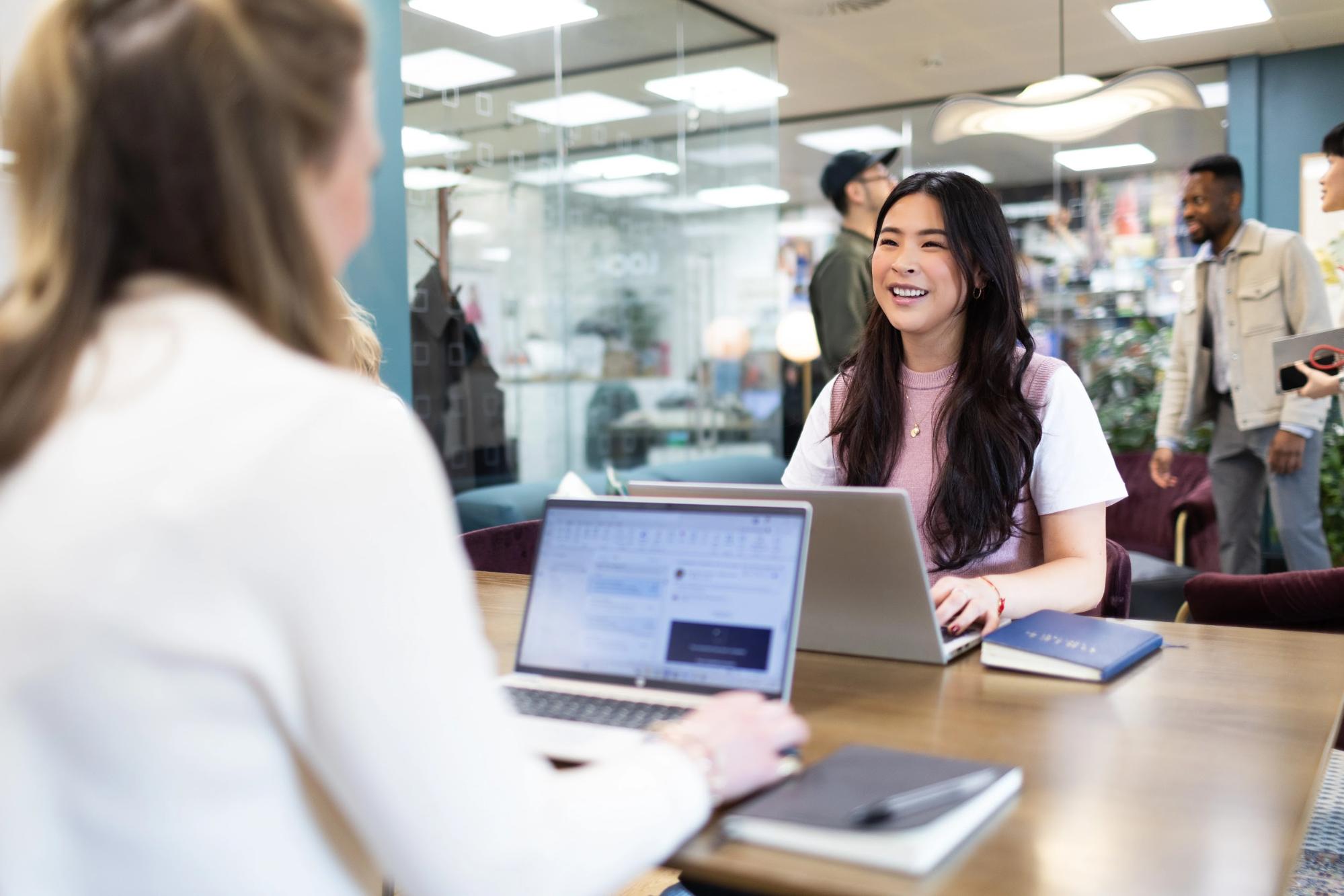 Two colleagues in conversation over a laptop in a bright start-up co-working space